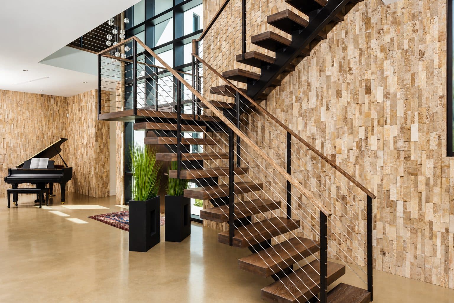 Craft House floating walnut stair with cable rail and full-height travertine mosaic feature wall